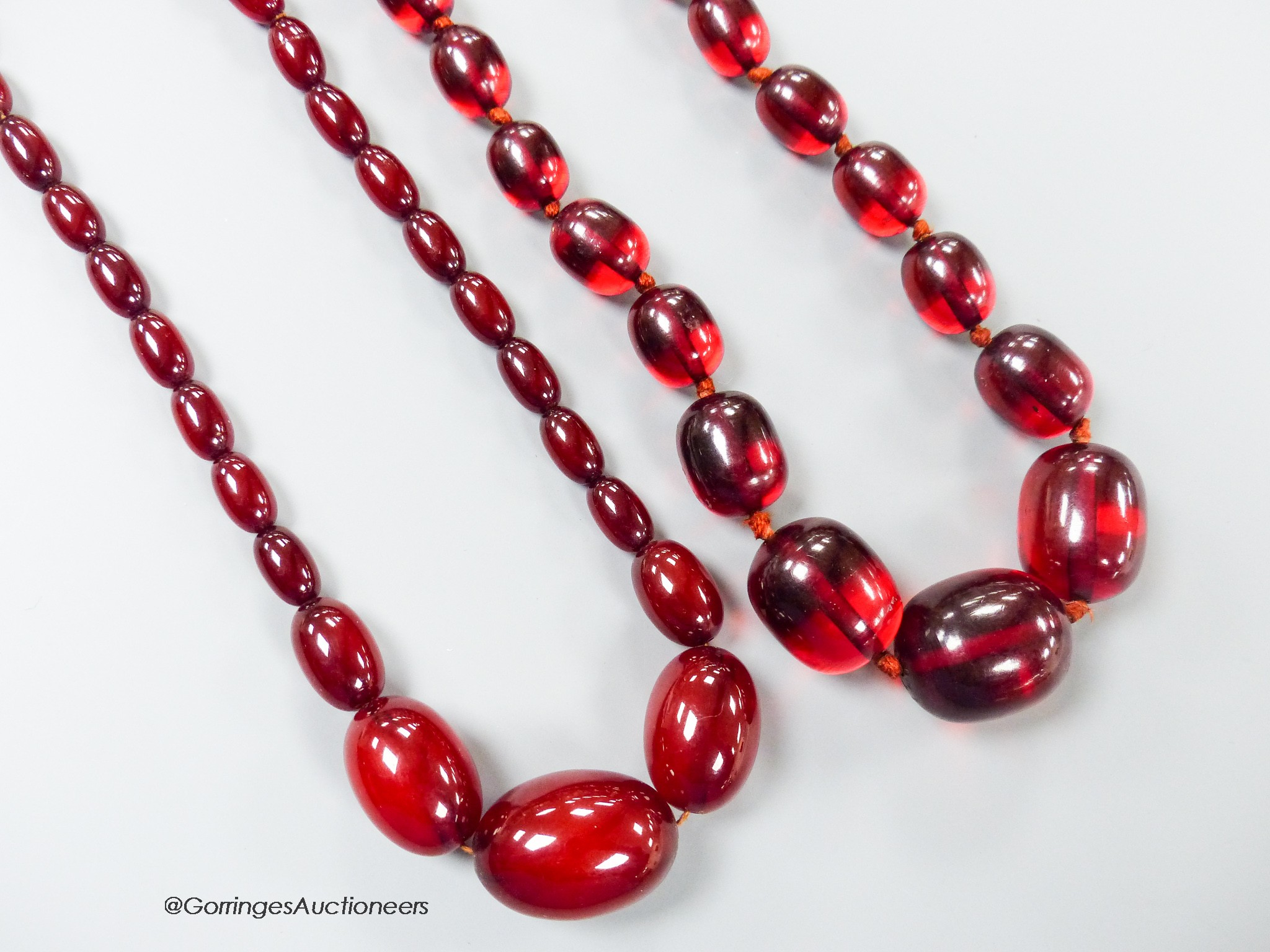 Two single strand graduated simulated cherry amber oval bead necklaces, longest 98cm, gross weight 134 grams.